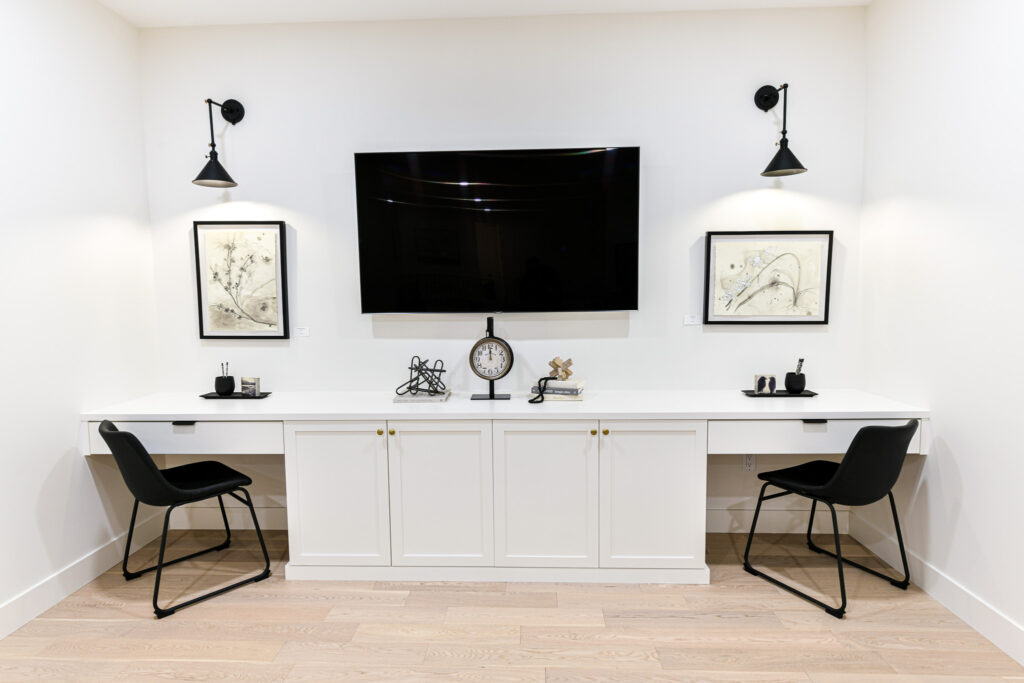 Monarch Homes, office area, showcasing a wall mounted TV, two chairs, and modern white cabinets in Grande Prairie, Alberta, Canada.